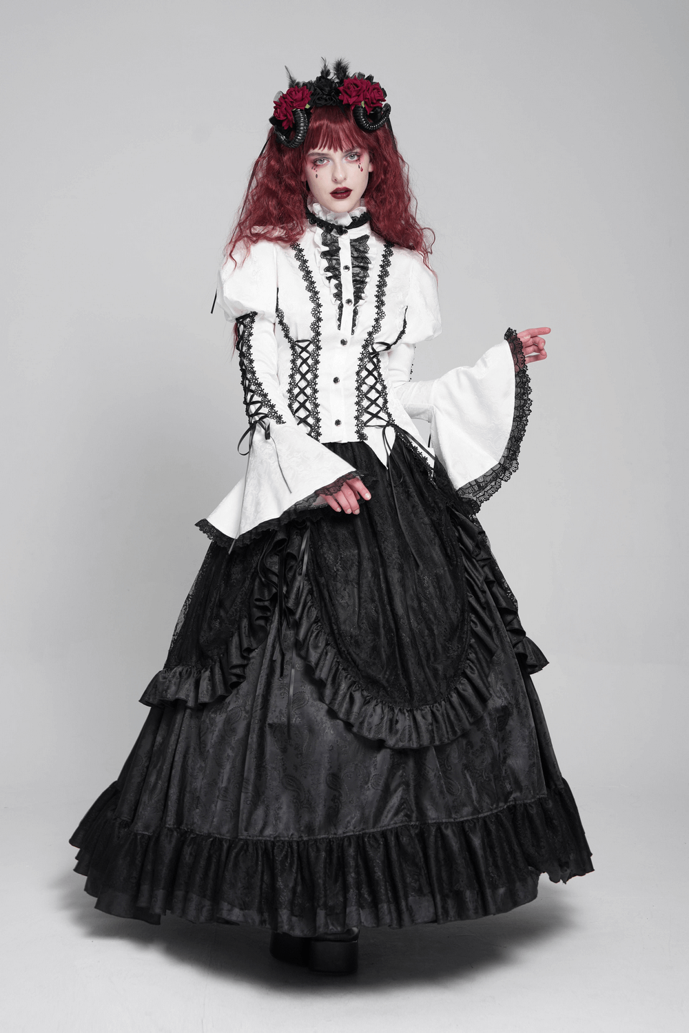 Model wearing a white gothic Victorian blouse with corset ties and a black ruffled skirt, styled for a dramatic look.