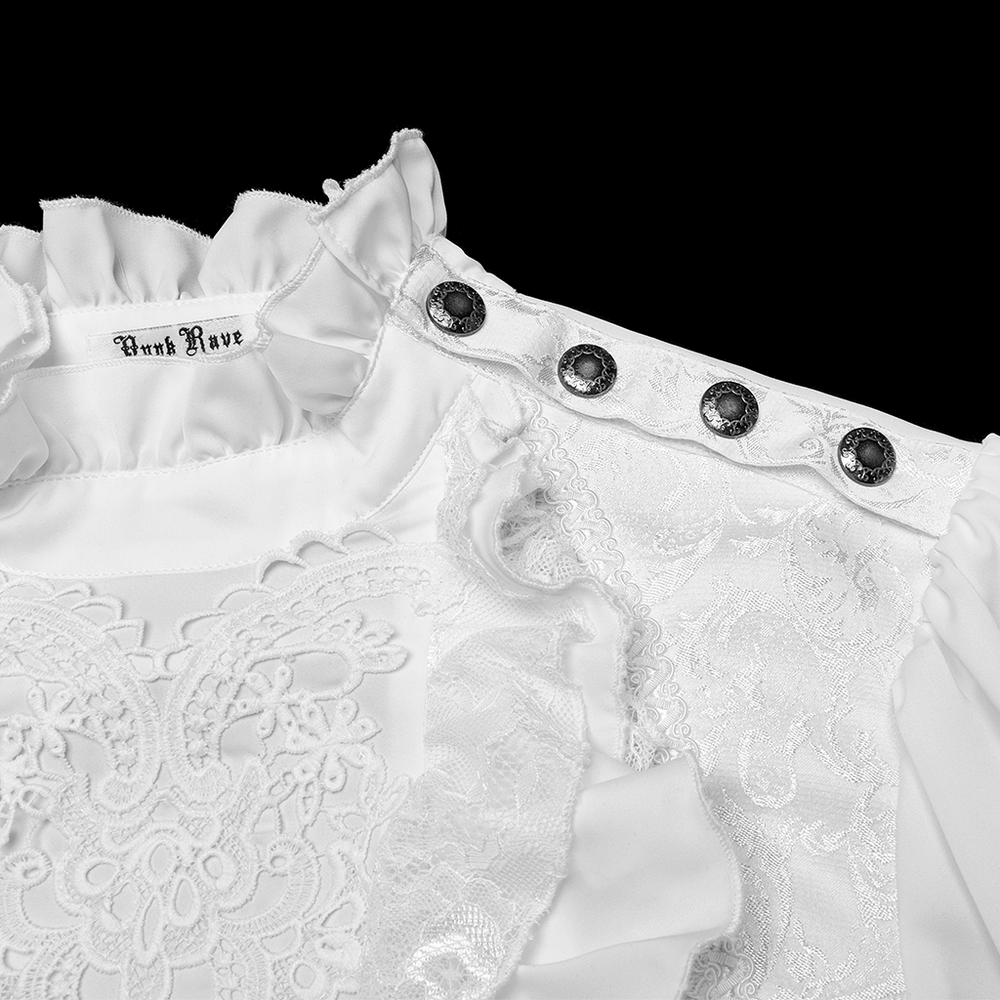 Close-up of a white lace-trimmed shirt featuring ruffles and engraved snap buttons, showcasing intricate design details.
