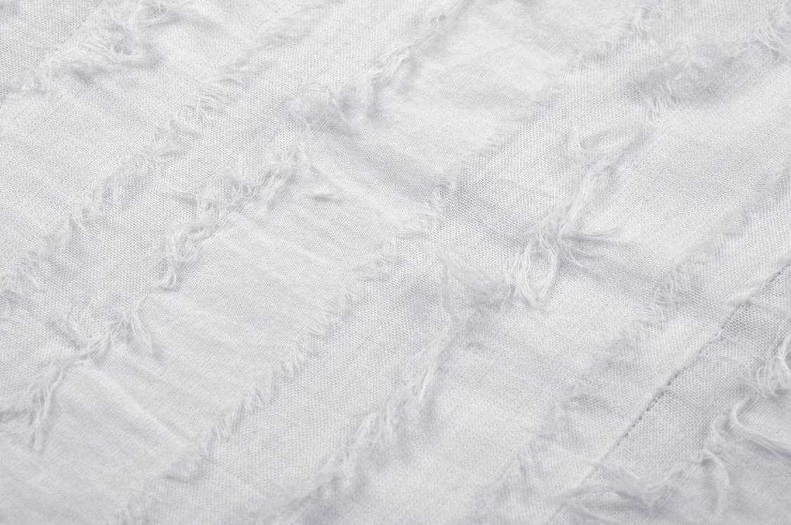 Close-up of textured white fabric with frayed details, perfect for a punk-style crop top.