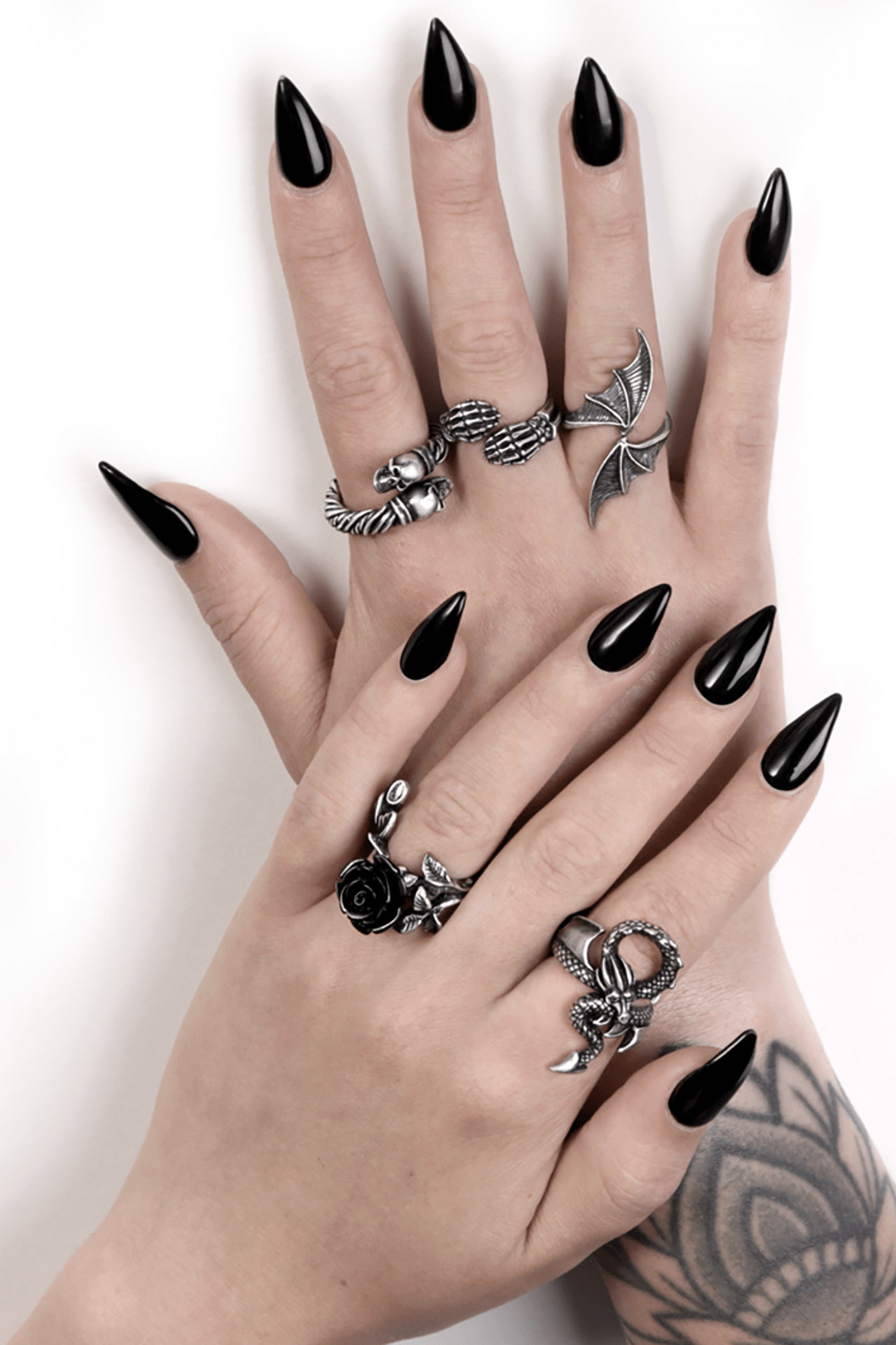 Hands displaying stylish rings, including a wild black rose ring in pewter, with black long nails.