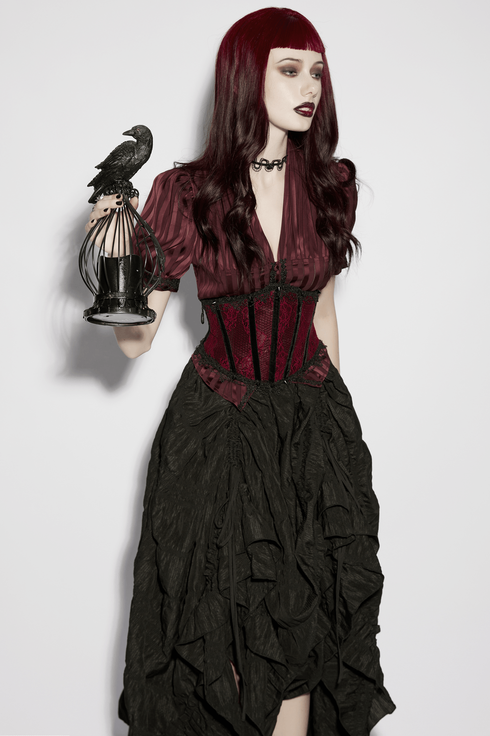 Wine Red Black Lace Up Gothic Waist Cincher Corset on gothic model with black skirt, holding birdcage prop—dramatic vampy look