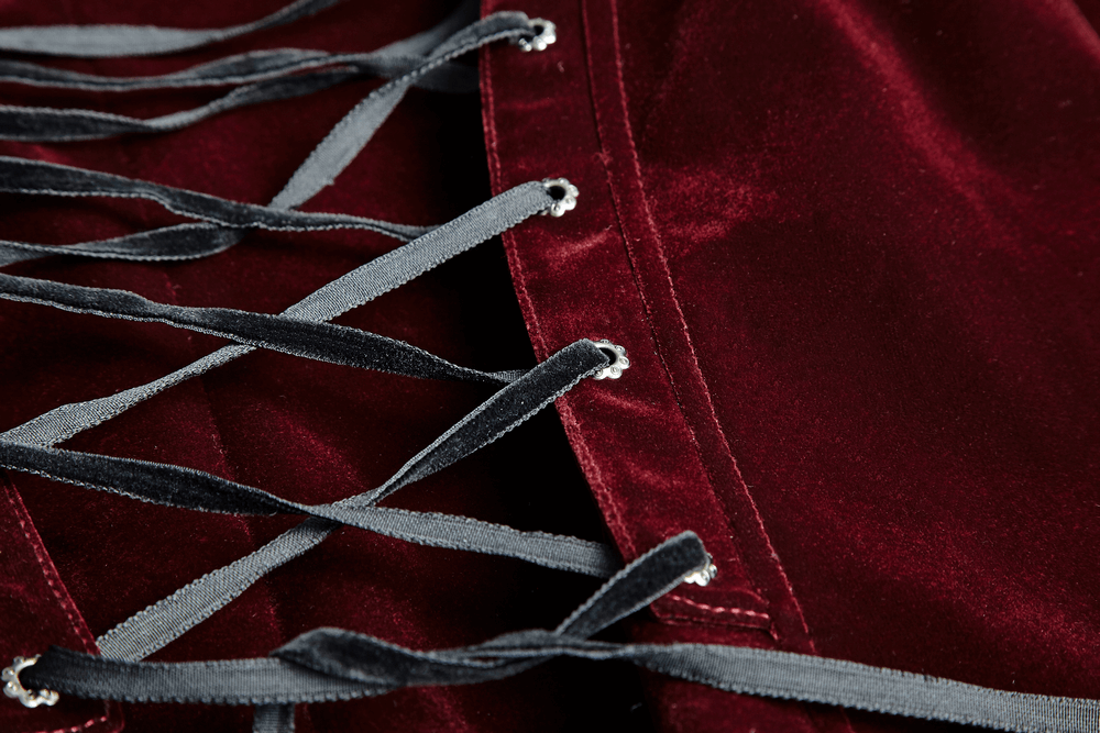 Close-up of wine red velvet fabric with intricate lace-up detailing in contrasting grey ribbons.