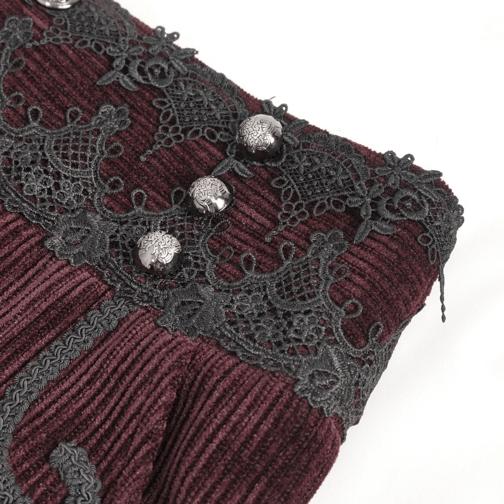 Close-up of wine red corduroy trousers featuring intricate black lace trim and metallic buttons.