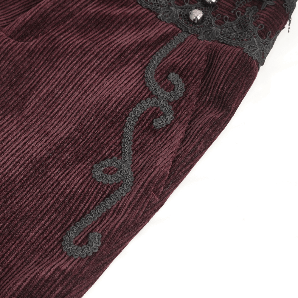 Close-up of wine red corduroy trousers with intricate black lace trim detailing.