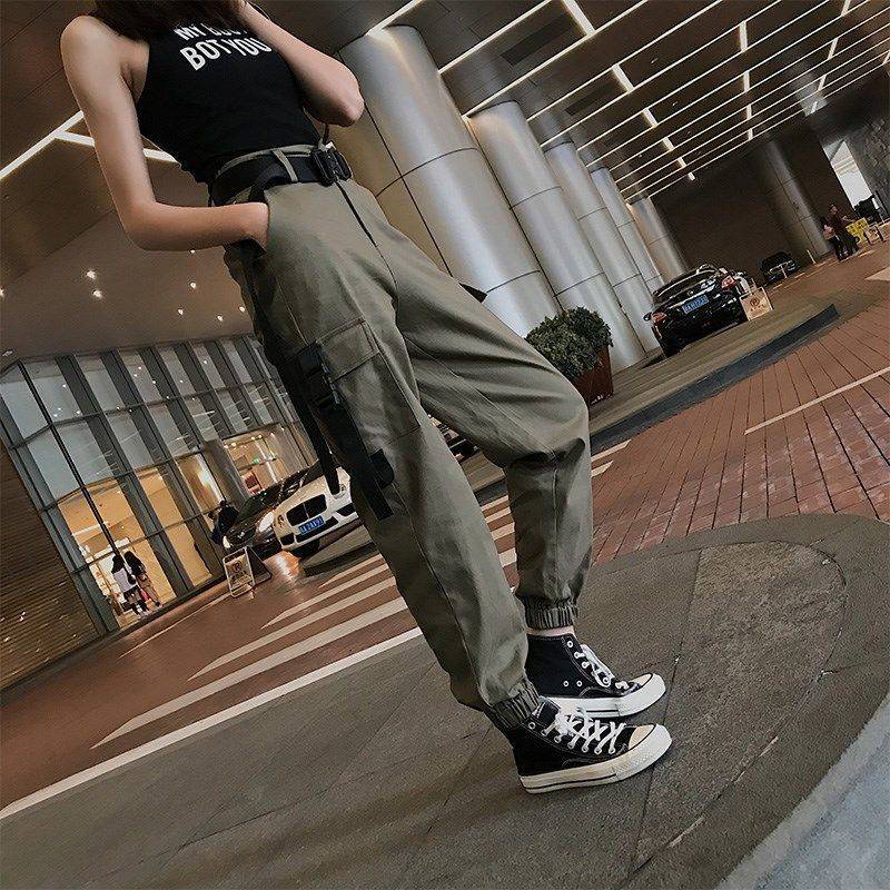 Stylish woman in high-waisted cargo joggers and sneakers, showcasing rock style fashion in an urban setting.