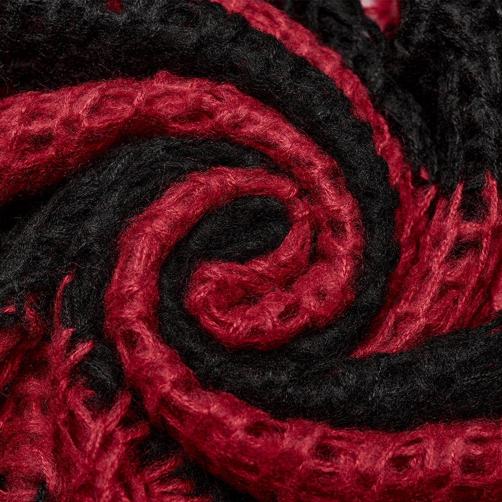 Close-up of a mohair fabric swirl featuring gothic black and red stripes, showcasing texture and bold color contrast.