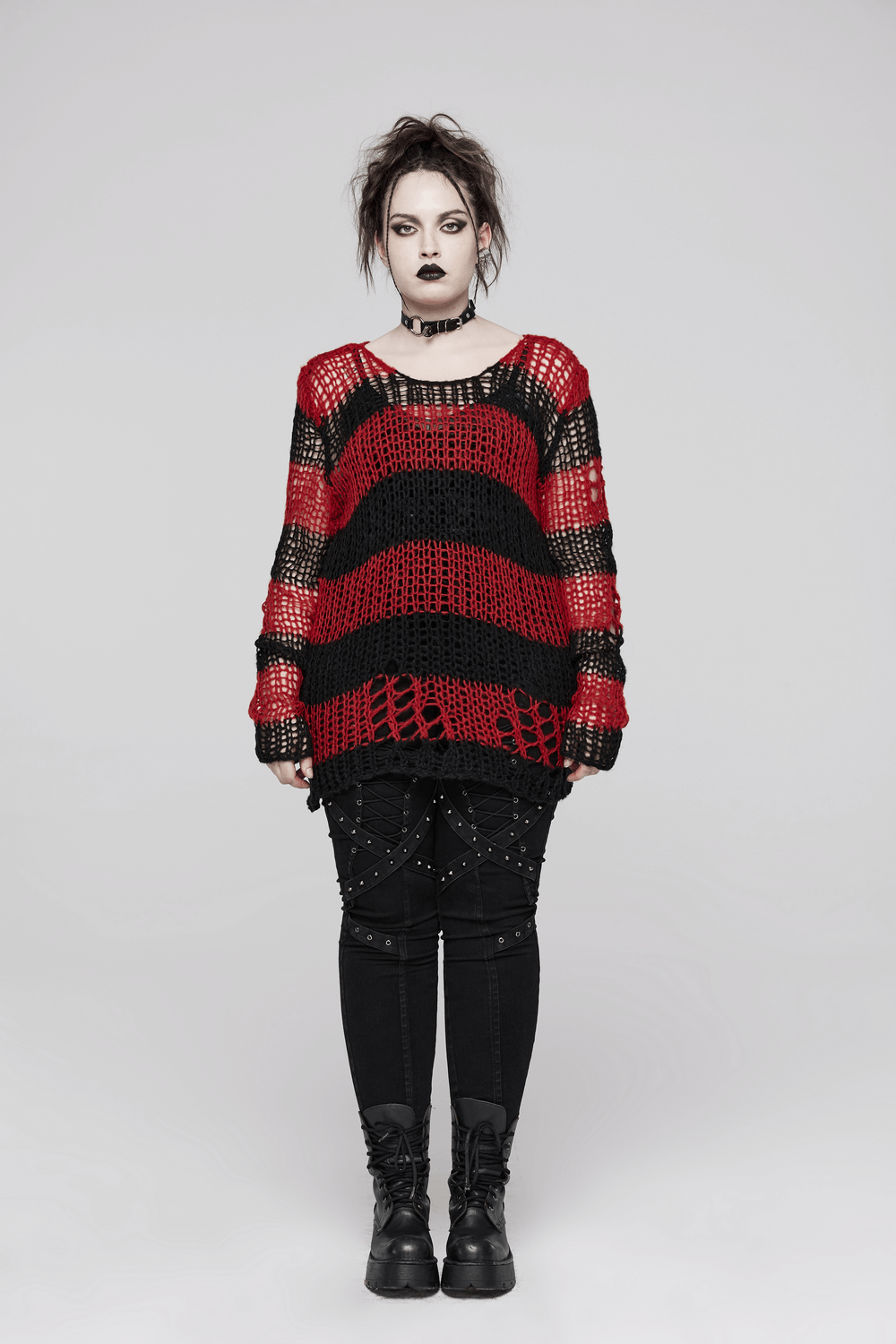 Women in a gothic striped mohair pullover sweater with edgy holes, paired with punk-inspired black pants and accessories.