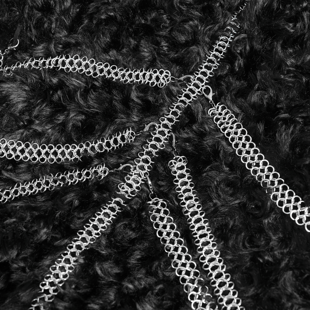 Close-up of layered silver chains on gothic faux fur fabric, adding dark elegance to an alternative hooded cape.