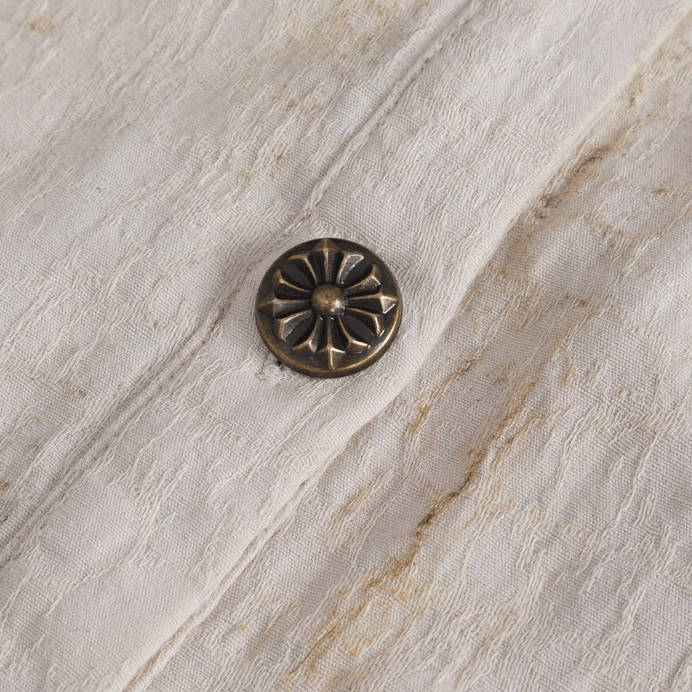 Close-up of antique button on a vintage ruffled shirt, showcasing intricate design and elegant texture.