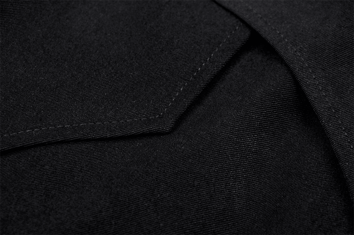 Close-up of the black fabric texture of a women's asymmetrical mini skirt, highlighting the stitching details.