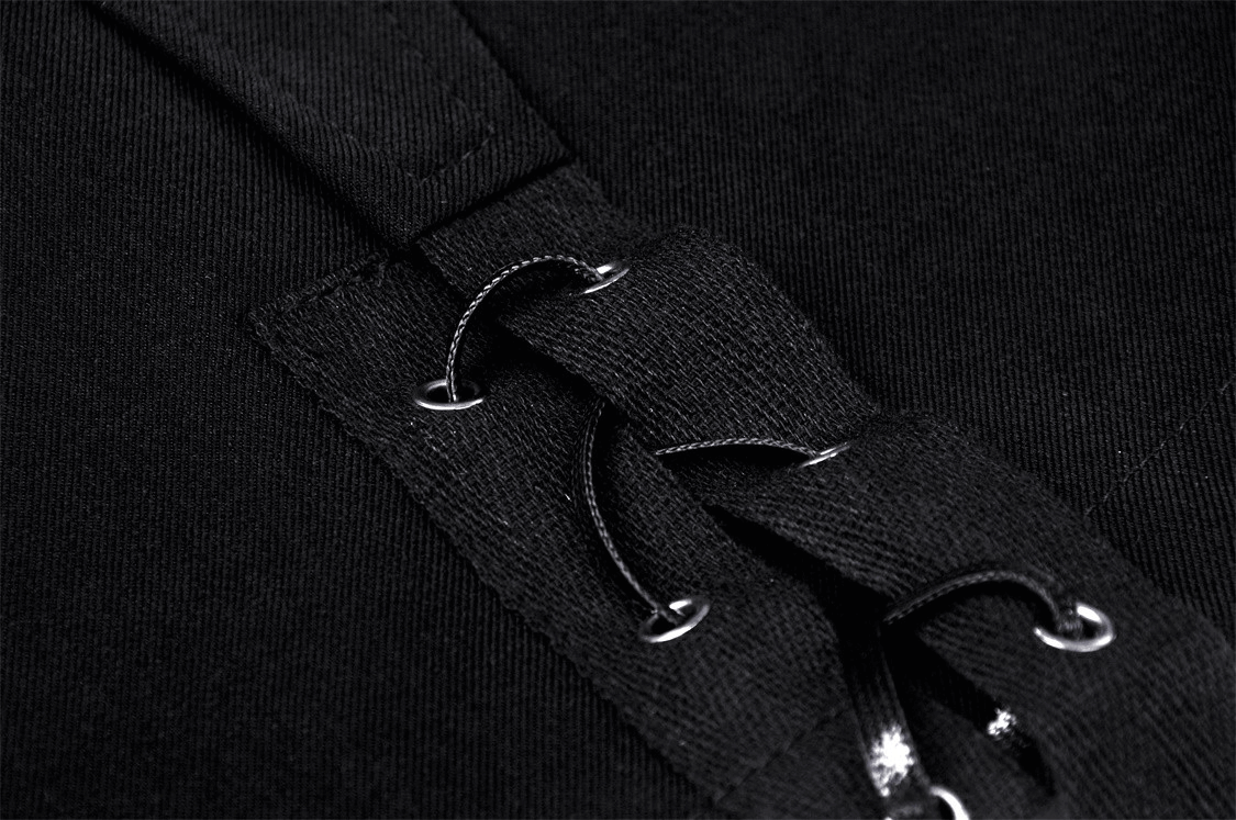 Close-up of black fabric with button straps on an asymmetrical mini skirt, showcasing punk rock style.