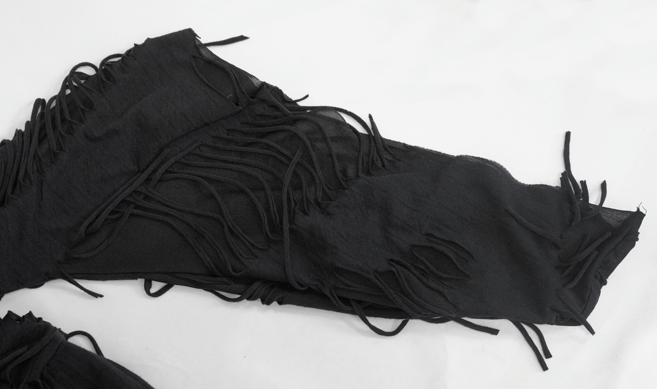 Close-up of black kimono dress sleeves with unique ripped design and long wide lacing fringes.
