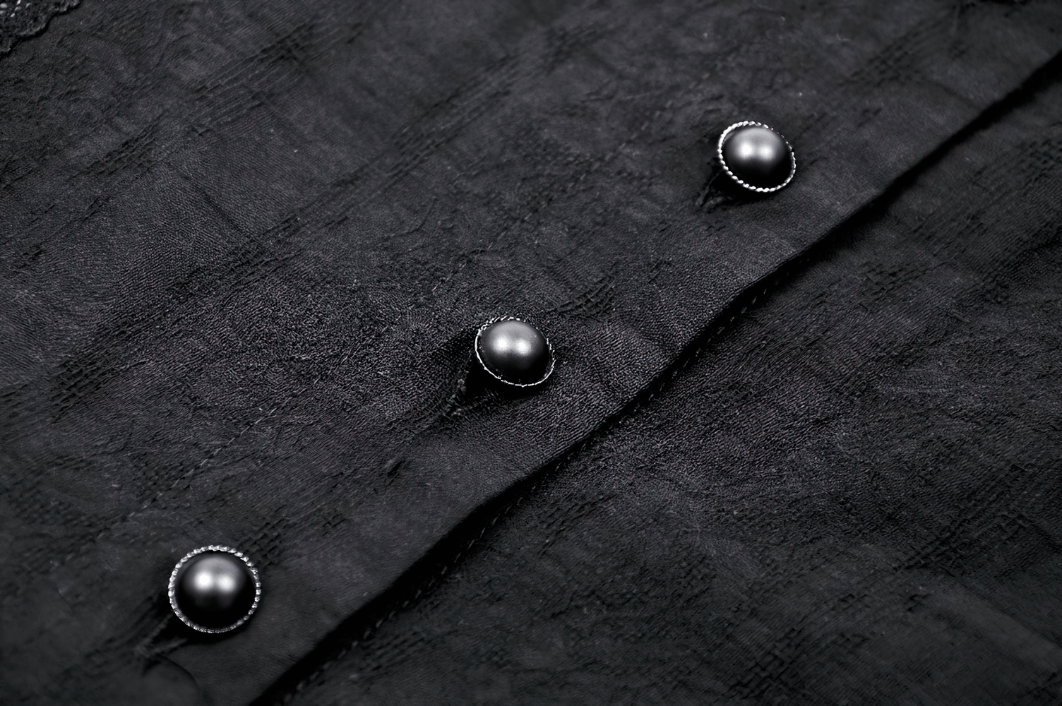 Close-up of black lace blouse buttons, showcasing gothic elegance and intricate design details.