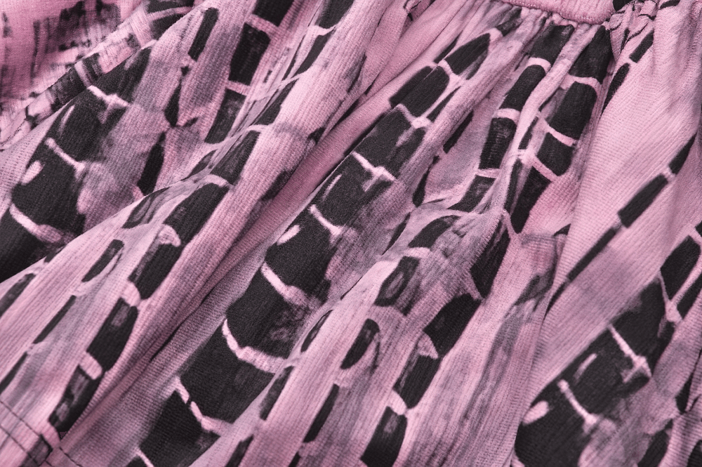 Pink tie-dye pattern on black fabric of a women's punk-inspired corset dress.