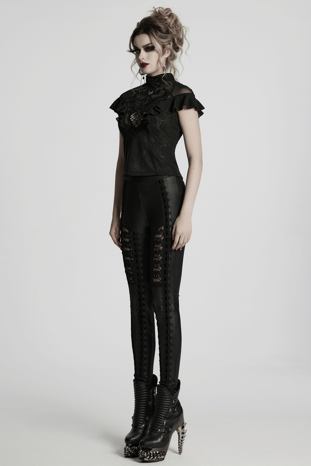 Gothic women's black lace ruffle top with embroidered applique, styled with edgy leather leggings and heels.