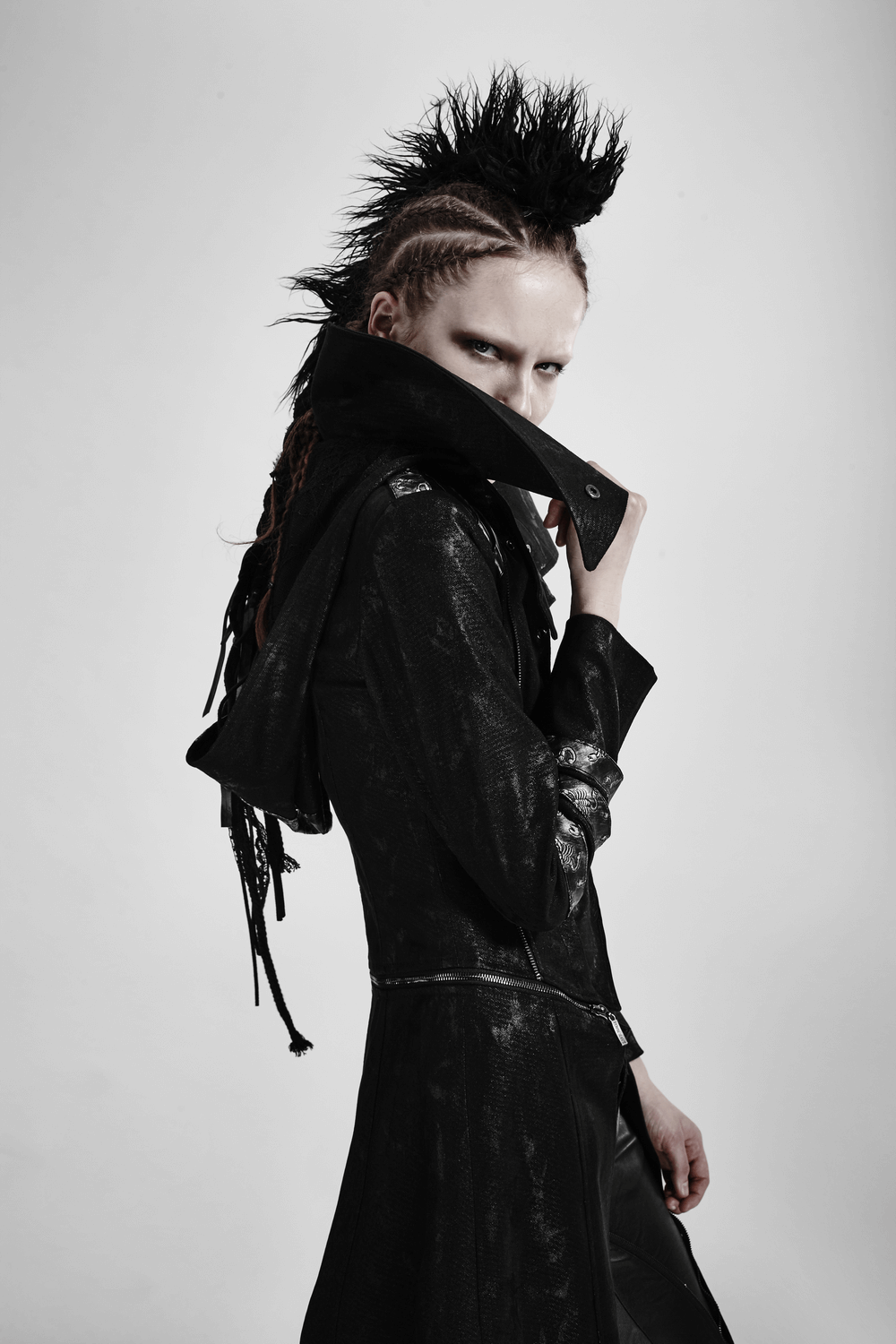 Gothic woman wearing a black leather-look long coat with a stand collar and edgy hairstyle, showcasing bold fashion.