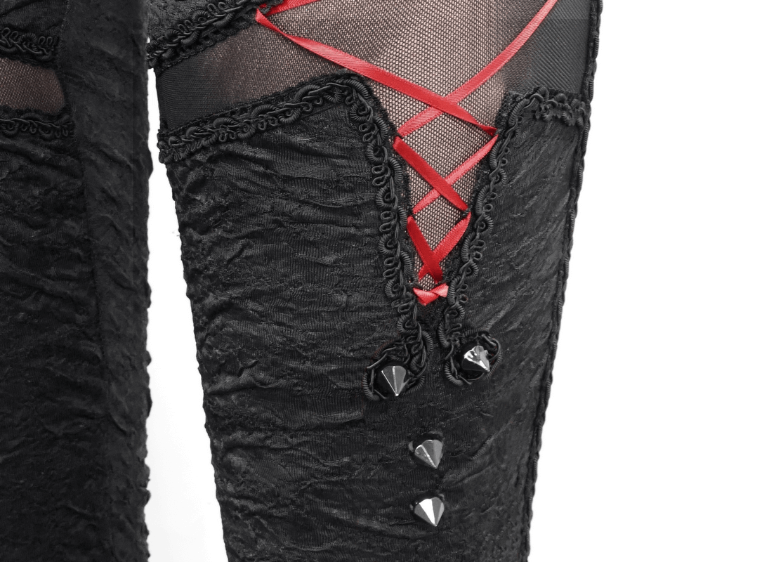 Close-up of women's gothic black leggings featuring red lacings and stylish torn inserts for a trendy look.