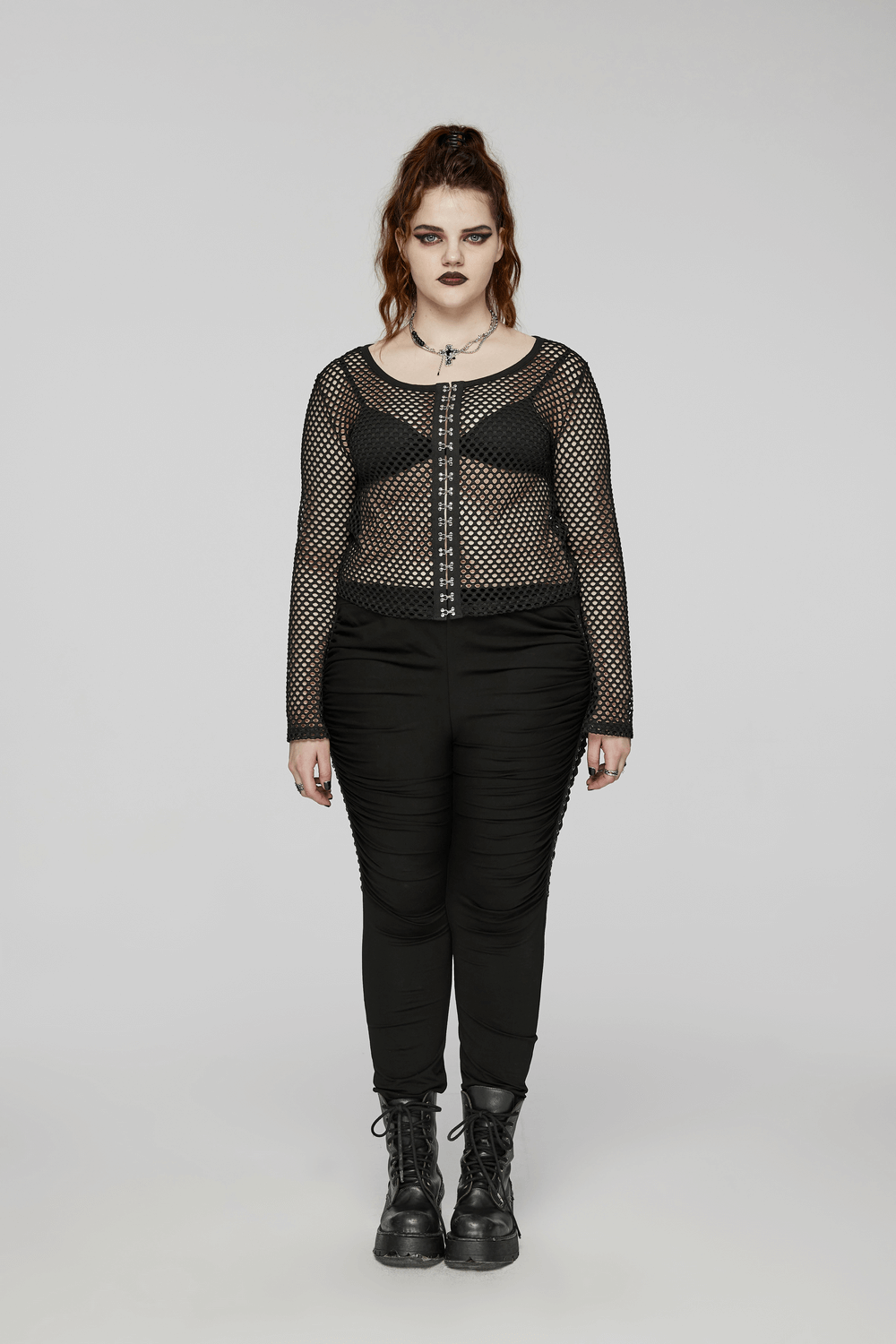 Bold women's black mesh layered zip top with long sleeves, paired with stylish black pants and combat boots.