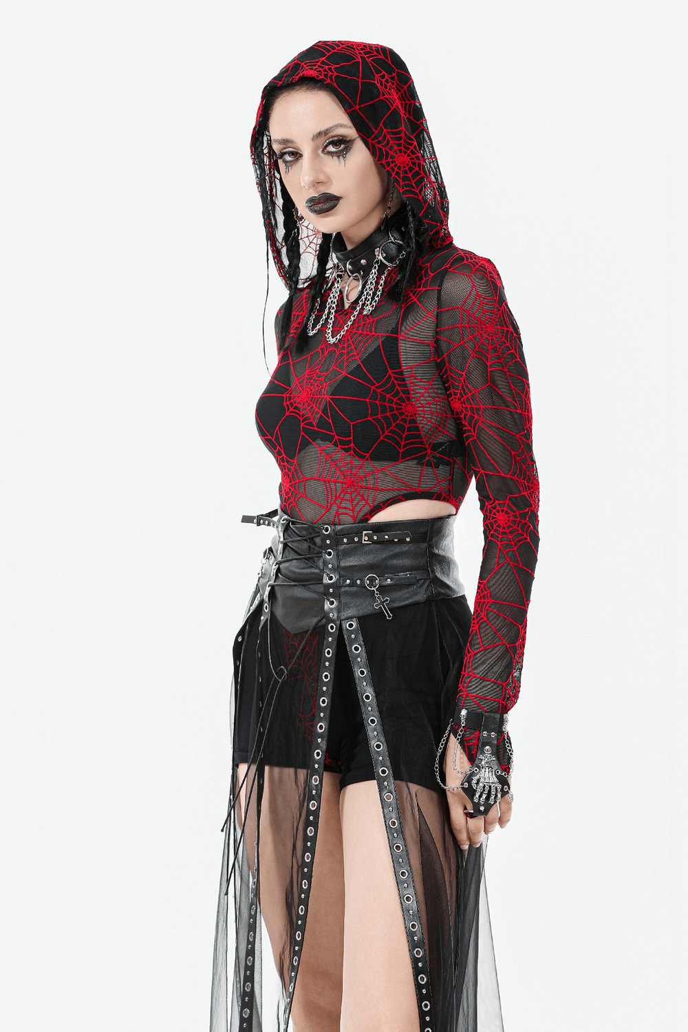 Gothic model in red spider web top and black sheer skirt with lace-up waist and stud accents, showcasing edgy alternative fashion.