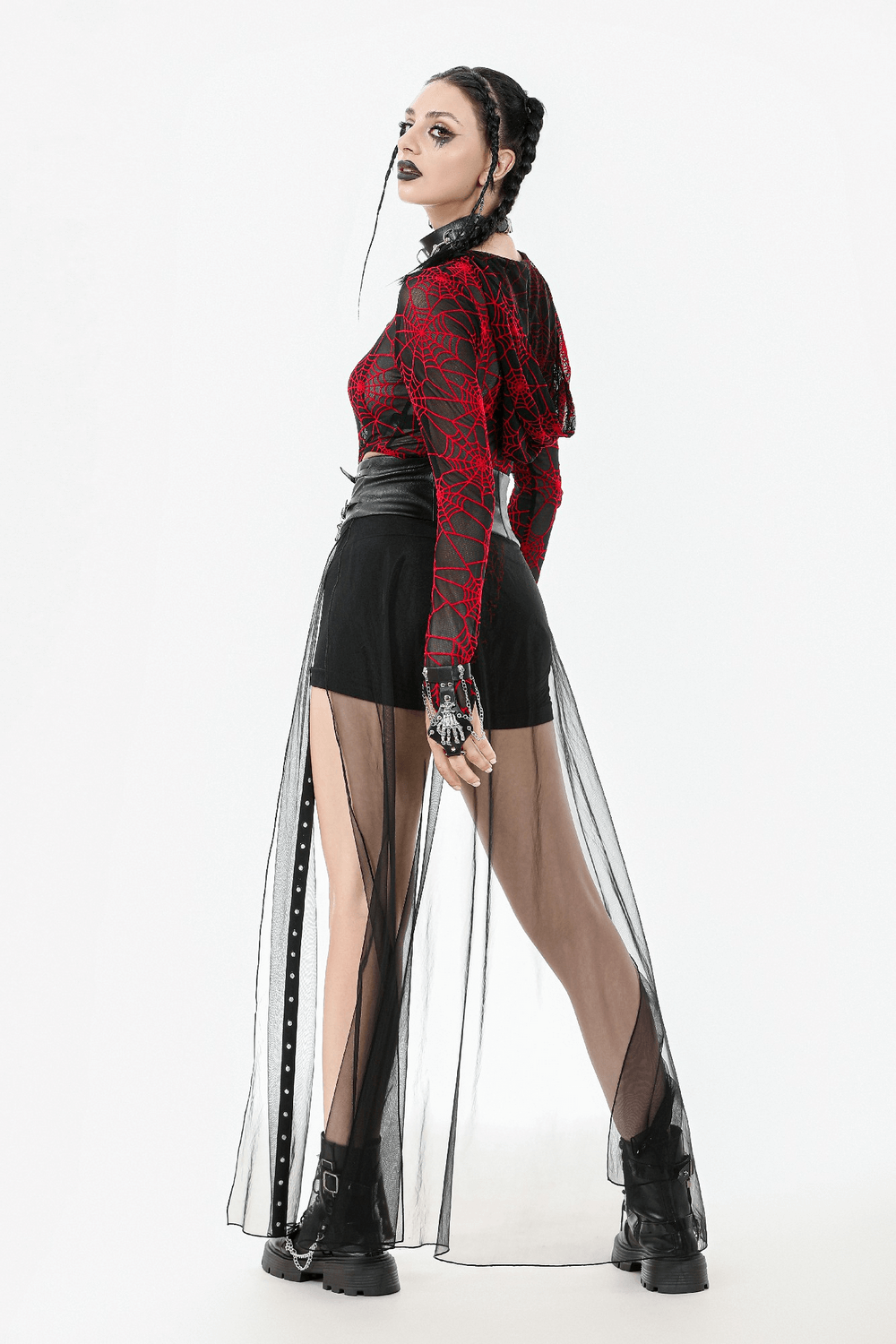 Model wearing a gothic sheer maxi skirt with lace-up waist and stud details, combined with an edgy red spiderweb top.