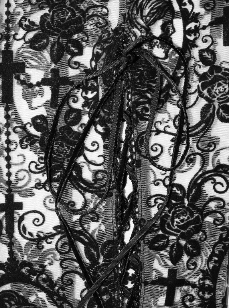 Close-up of intricate lace detailing and gothic print featuring skeletons and roses on women's black leggings.