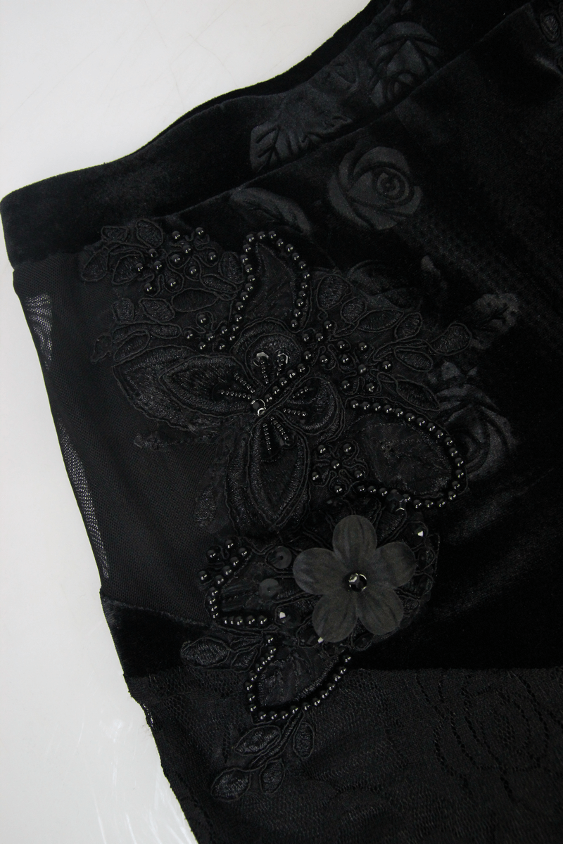 Detailed view of black velvet pants featuring lace and embroidered floral designs, embodying gothic elegance.