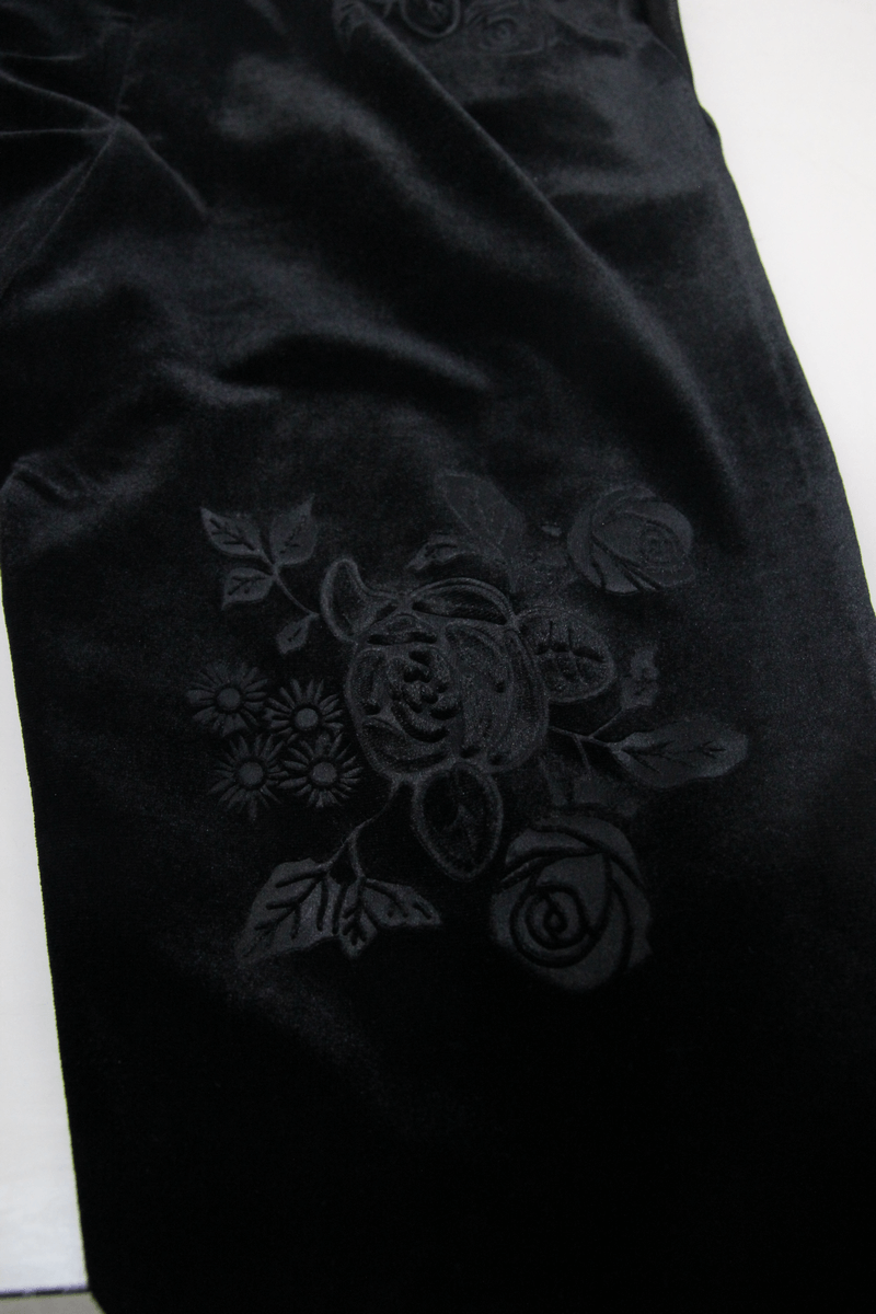 Close-up of elegant black velvet pants featuring intricate floral lace embroidery, perfect for a gothic style wardrobe.