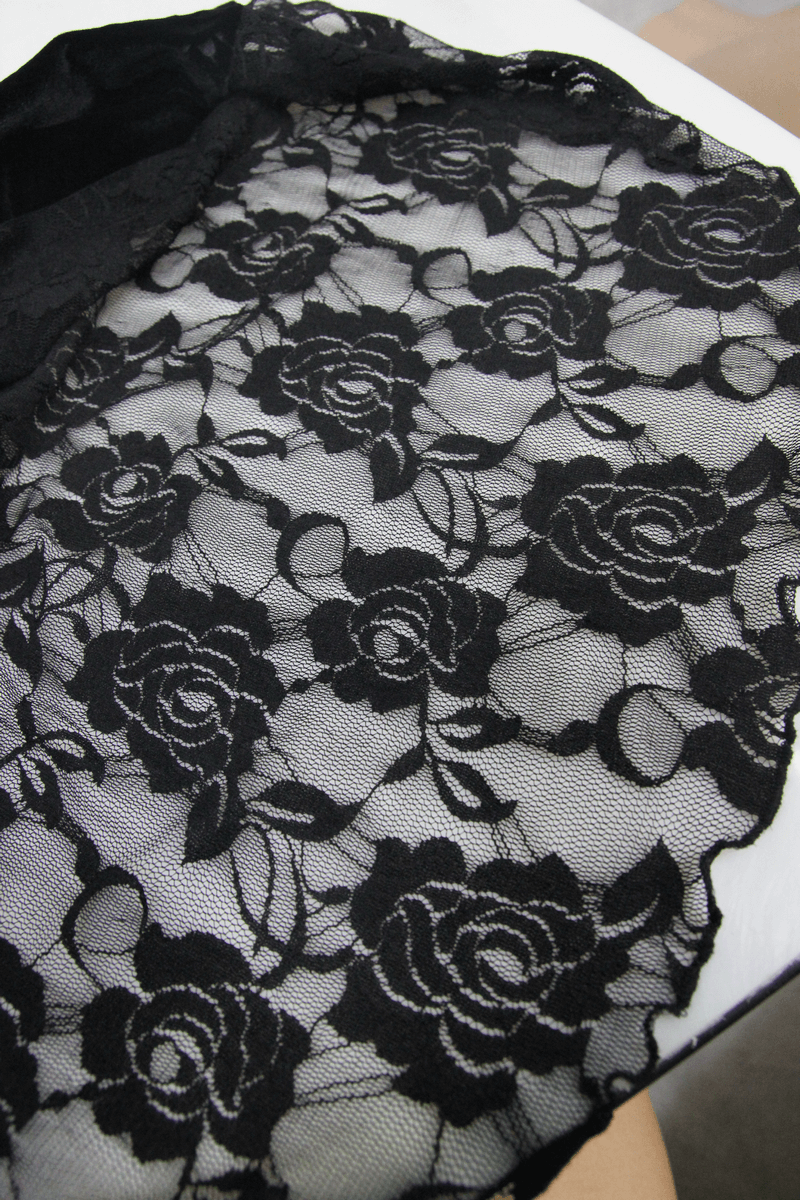 Black lace fabric featuring elegant rose patterns, perfect for gothic fashion and stylish designs.