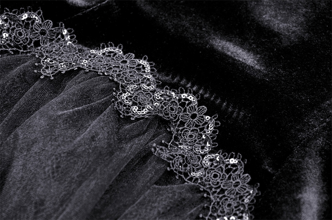 Close-up of elegant black velvet fabric with intricate lace hem, showcasing gothic high-low dress detail.