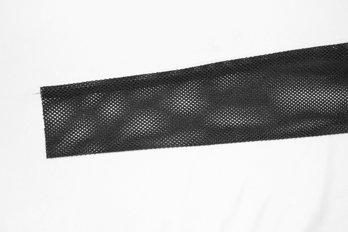 Close-up of black mesh fabric highlighting texture for punk-style women's bodysuit design.