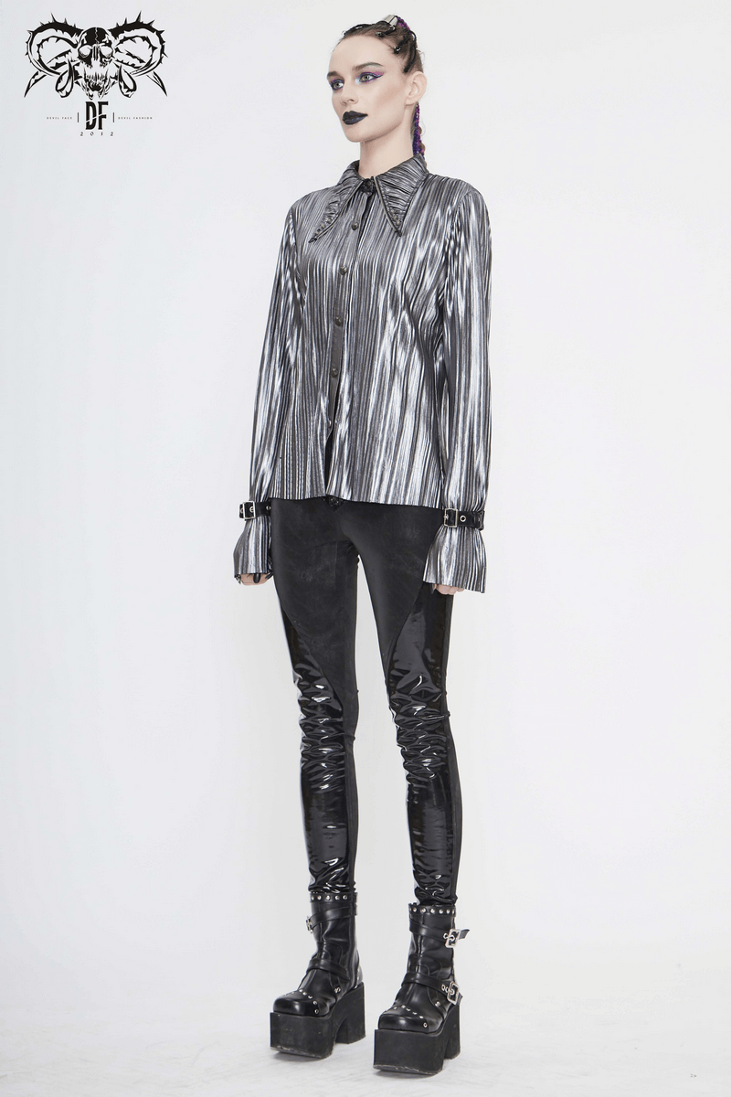 Stylish woman in a bright silver shimmer long ruffle-sleeved blouse paired with shiny black leggings and chunky platform boots.