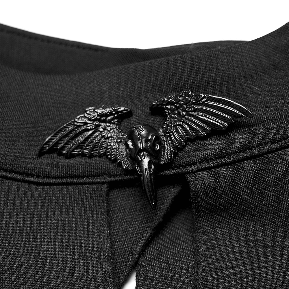 Matte black bird-head pin with wings on dark fabric for gothic cape or outfit.