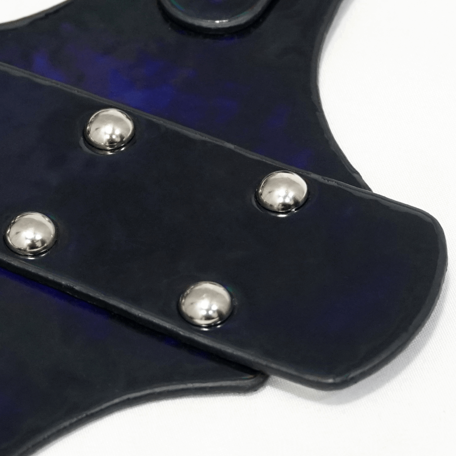 Close-up of a women's faux leather gothic body harness with shiny silver fittings and a sleek black design.