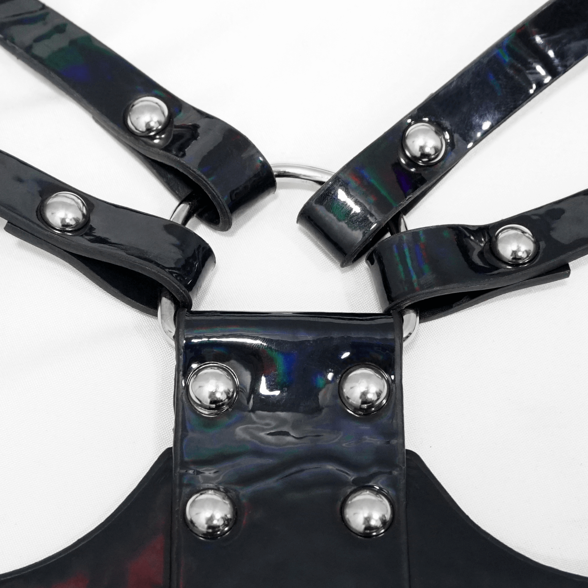 Close-up of a women's gothic faux leather body harness featuring shiny black straps and silver fittings.