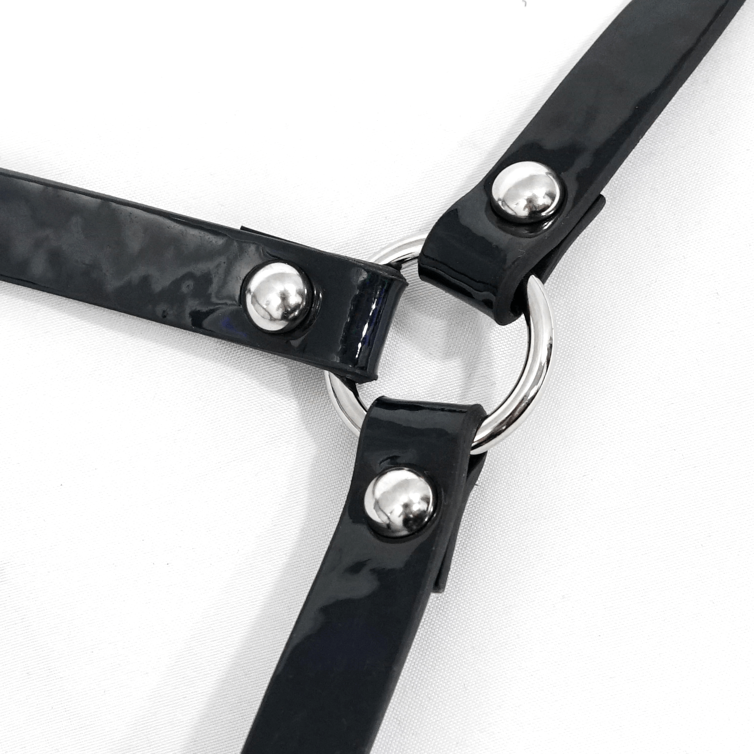 Close-up of a women's gothic faux leather body harness with silver fittings and a central ring.