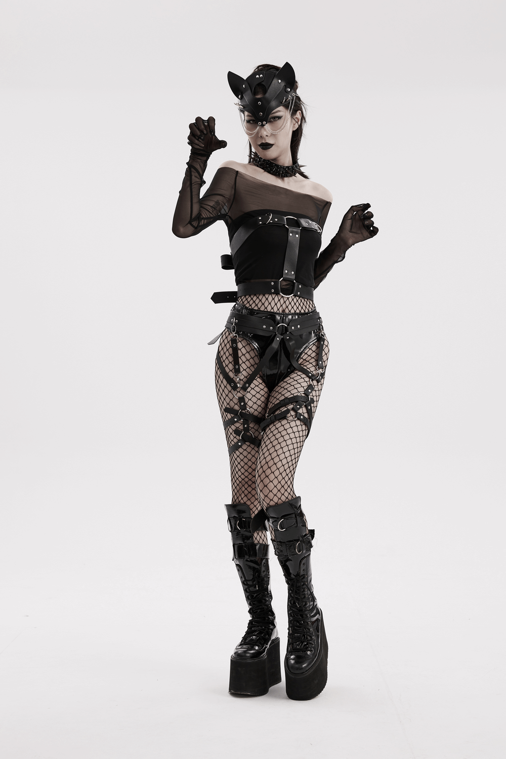 Edgy woman in faux leather Gothic harness, fishnet stockings, and platform boots, embodying punk fashion style.