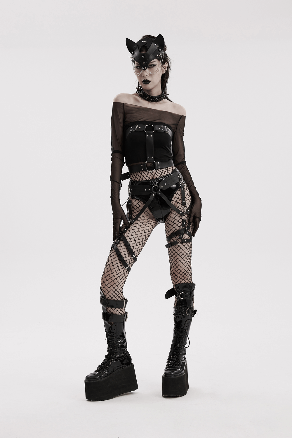 Model in a faux leather gothic strappy harness with fishnet tights and platform boots, embodying edgy punk style.