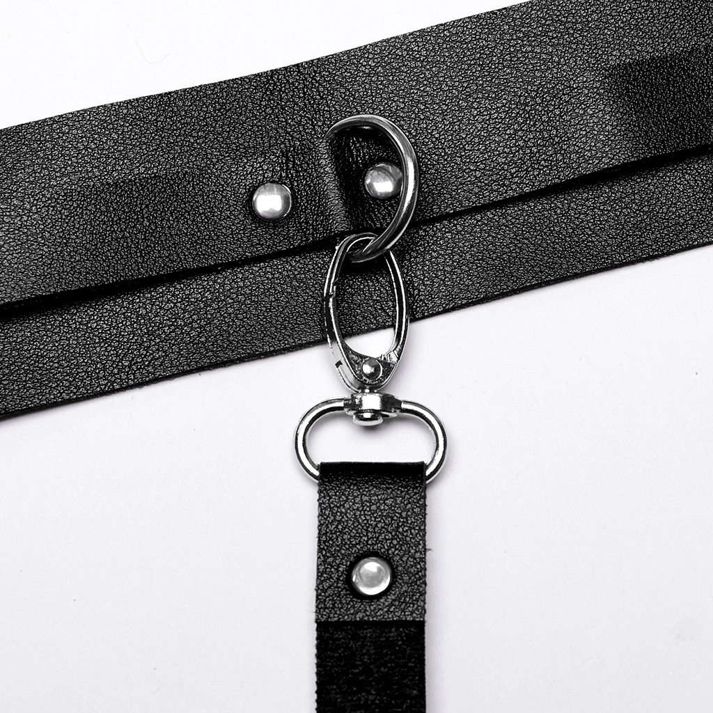Close-up of black faux leather harness clasp with silver hardware for punk fashion outfits.