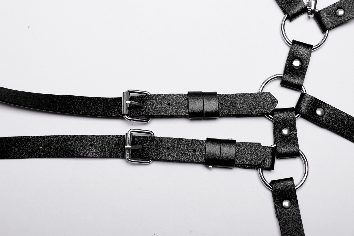 Edgy women's faux leather strappy harness with adjustable loops and silver rings for alternative fashion.
