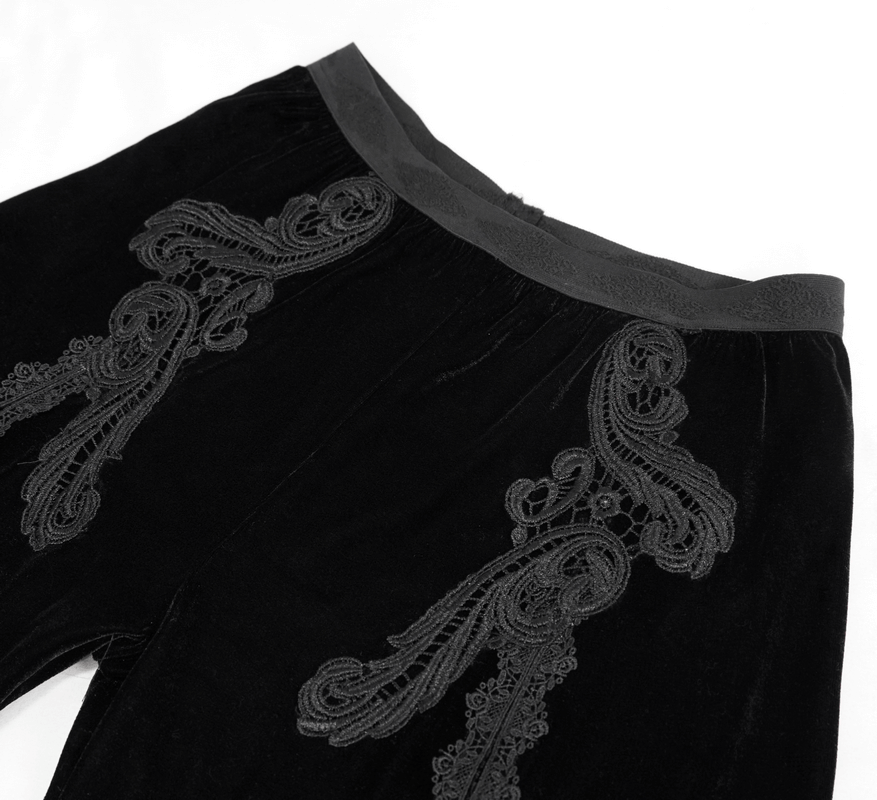 Close-up of women's gothic black velvet flared pants with intricate lace embroidery details.