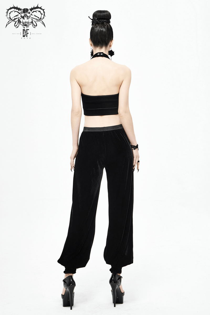Back view of a model in black velvet flared pants and a matching crop top, showcasing gothic fashion style.