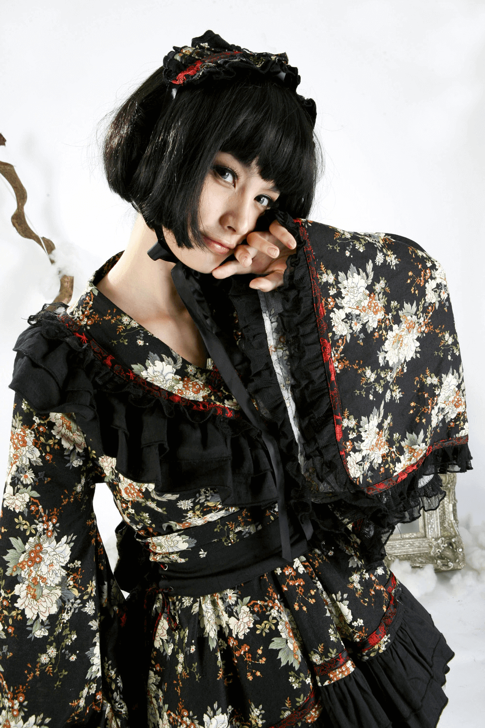 Woman in a black floral Gothic Lolita dress with ruffles, showcasing Victorian elegance and unique style.