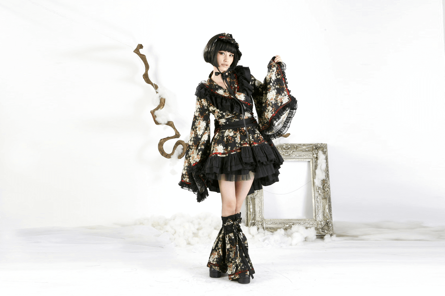 Stylish woman in black floral gothic Lolita dress with ruffles and lace, perfect for themed events and cosplay.