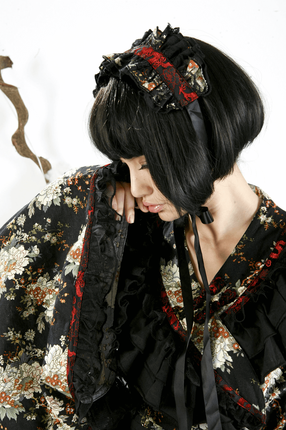 Model in black floral Gothic Lolita dress with ruffles and lace, showcasing Victorian elegance and unique style.