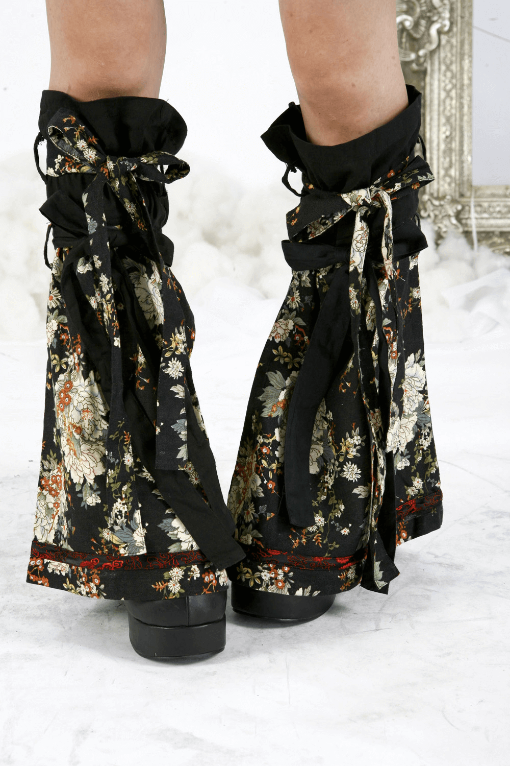 Close-up of floral gothic-inspired leg decorations on women's black dress, showcasing unique ruffles and lace details.
