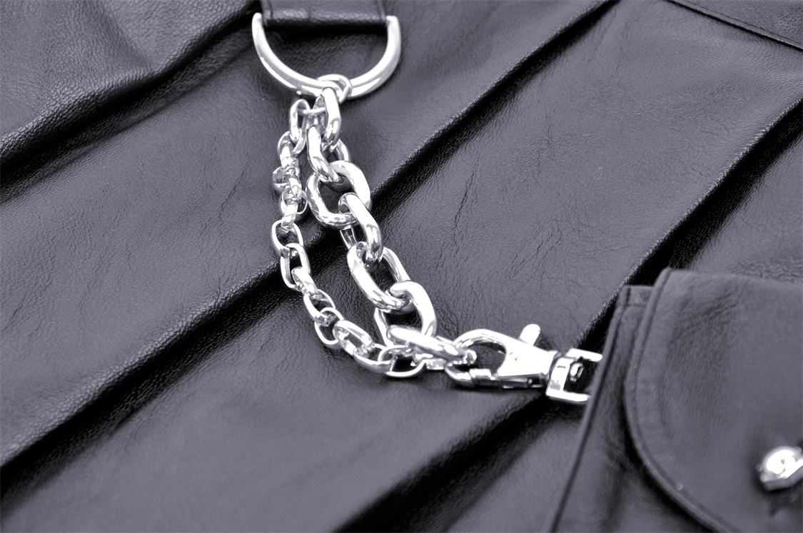 Close-up of a silver chain with a clip on a black pleated mini skirt, highlighting its edgy gothic punk style.