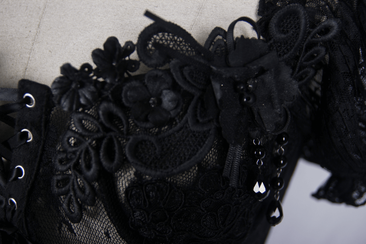 Close-up of a black lace corset featuring floral embellishments and intricate vintage patterns.