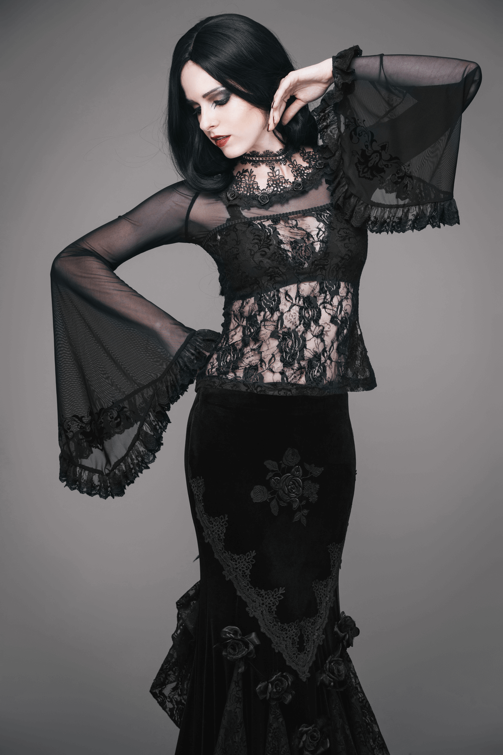 Elegant gothic model wearing a black lace corset and flowing dress, showcasing vintage style and intricate detailing.