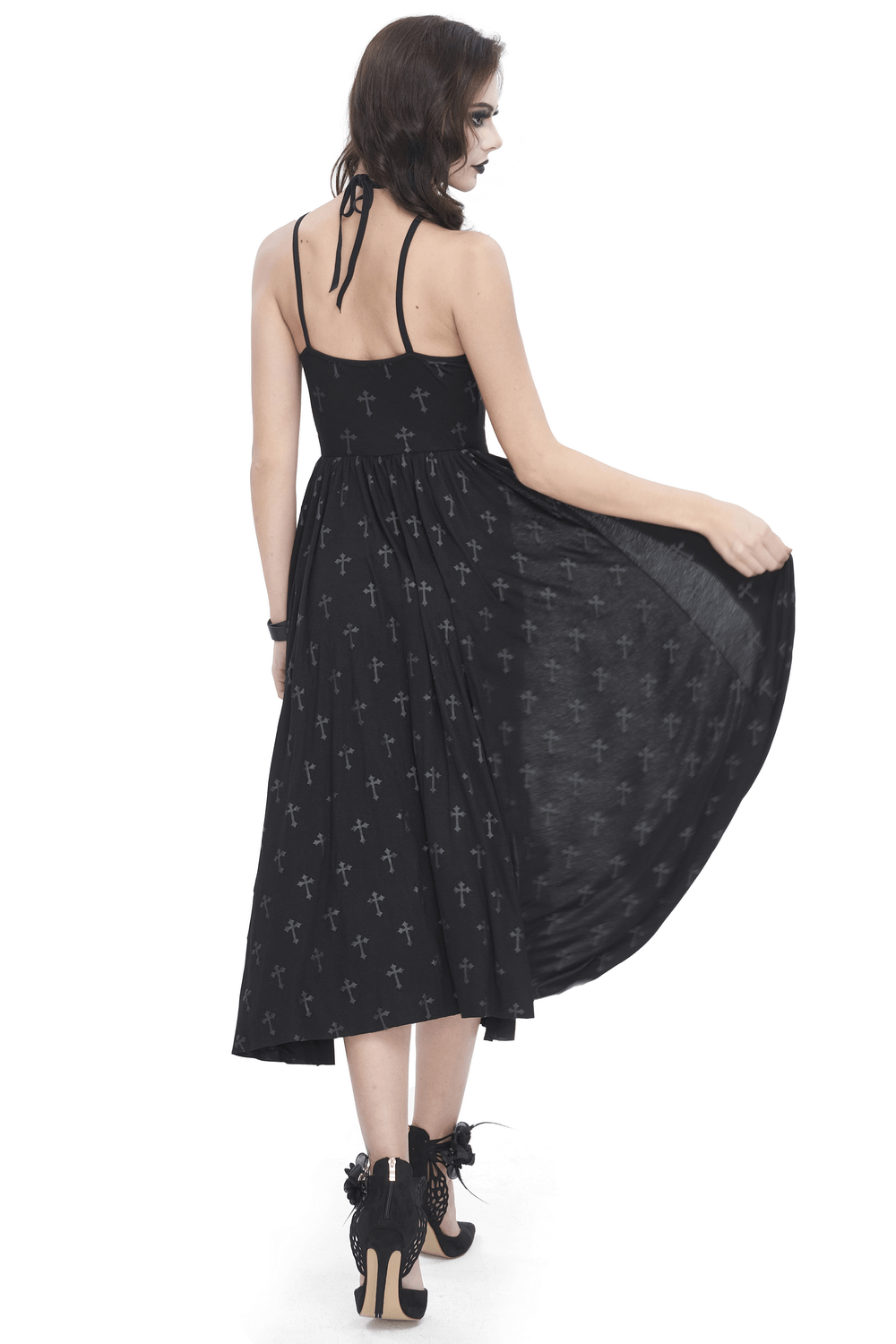 Stylish woman in a black gothic maxi dress with cross patterns, showcasing the back view and flowy skirt.