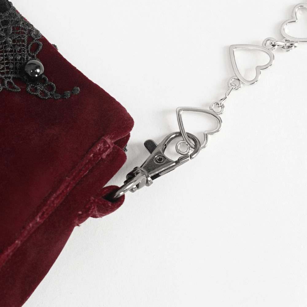 Close-up of gothic lace and velvet shoulder bag with heart chain accents and clasp detail.